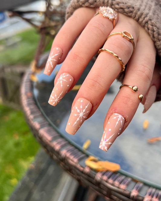 Winter christmas nude press on nails with a matte top coat and little shiny white snowflakes over the top.
