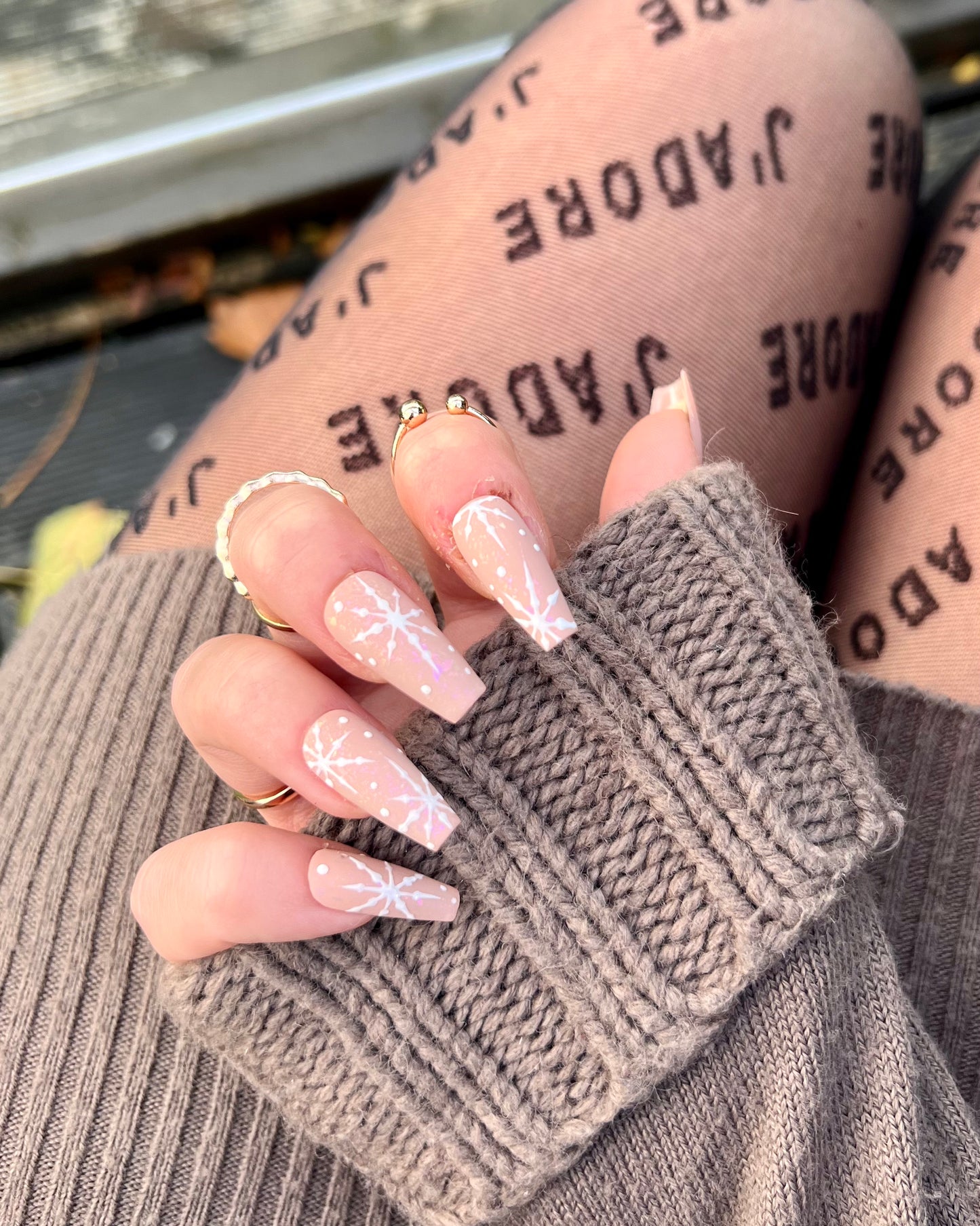 Christmas luxury affordable press on nails; nude base with pink opal sparkles and little white snowflake details.