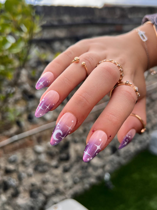 Purple chrome ombre on a pink nude base almond press on nails; white stars and moons details.