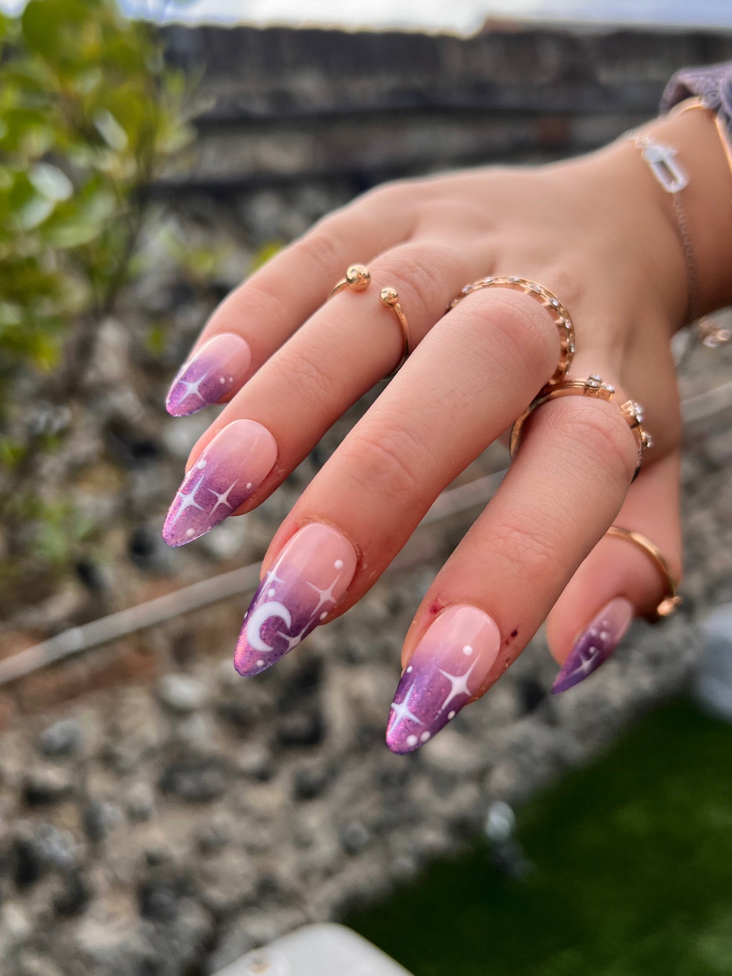 Purple chrome ombre on a pink nude base almond press on nails; white stars and moons details.